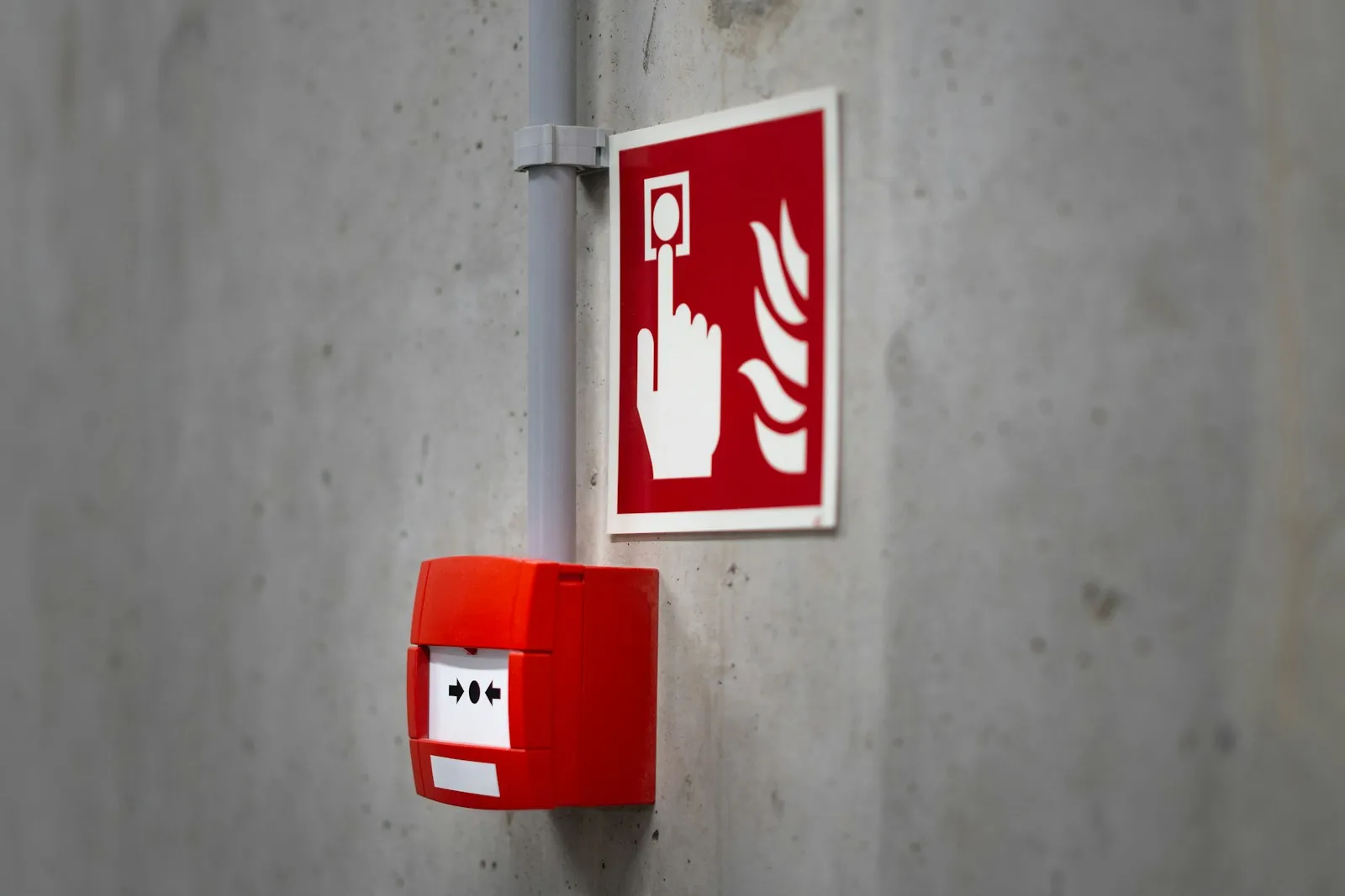 Handfeuermelder und Brandschutzkennzeichnung an einer Betonwand